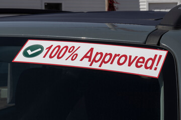 100% Approved sign at a Buy Here Pay Here used car lot. Many buy here pay here car dealerships do not require good credit but may track your car if you miss payments.