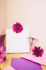 Mockup image with a white canvas surrounded by color papers and flowers