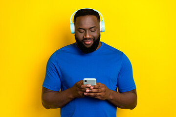Portrait of attractive cheery guy listening hit using device melody chatting isolated over bright...