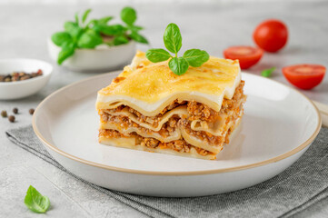 Slice of Lasagna bolognese with meat sauce and bechamel with melted cheese on top and fresh basil. Italian cusine. Copy space.