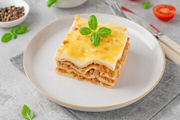 Slice of Lasagna bolognese with meat sauce and bechamel with melted cheese on top and fresh basil. Italian cusine. Copy space.