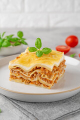Slice of Lasagna bolognese with meat sauce and bechamel with melted cheese on top and fresh basil. Italian cusine. Copy space.