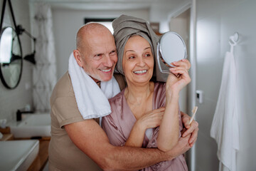 Senior couple in love in bathroom, looking at mirror and smiling, morning routine concept.