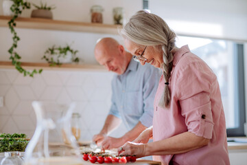 Happy senior couple cooking together at home.