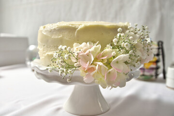 White Buttercream Wedding Cake on Stand Decorated With Hydrangeas and Babys Breath Flowers