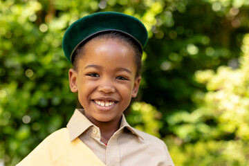 Portrait of smiling african american scout girl in uniform at forest - Powered by Adobe