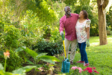 Cheerful african american senior couple gardening together in backyard - Powered by Adobe