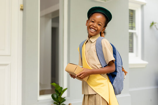 Portrait of smiling african american scout girl in uniform delivering package at home