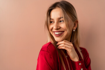 Fashion studio portrait of a happy young blonde woman posing over pink background.