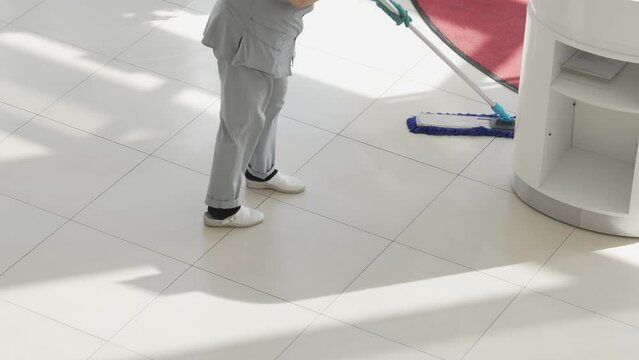 a female cleaner washes floors with a mop in the office or sales floor.