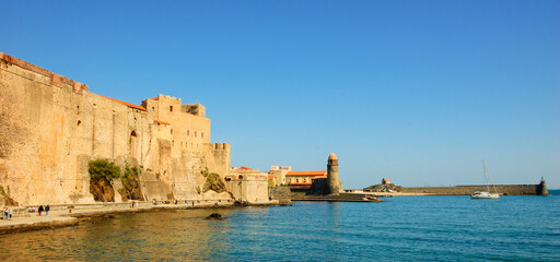 Collioure, South of France. Seaside promenade under medieval walls. Church and lighthouse at background. Travel banner © Elena Dijour