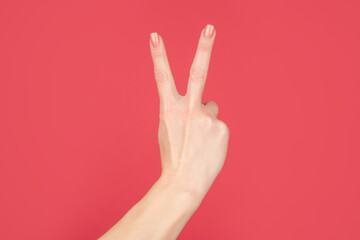 female hand showing peace gesture on red background