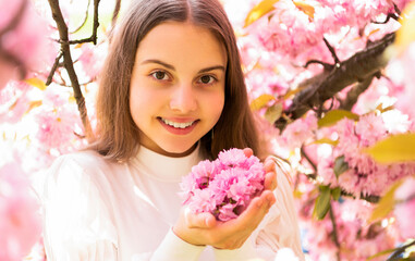 Fototapeta premium cheerful teen girl at sakura flower bloom in spring