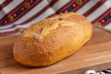 fresh white bread on brown wood cutting board on tablecloth