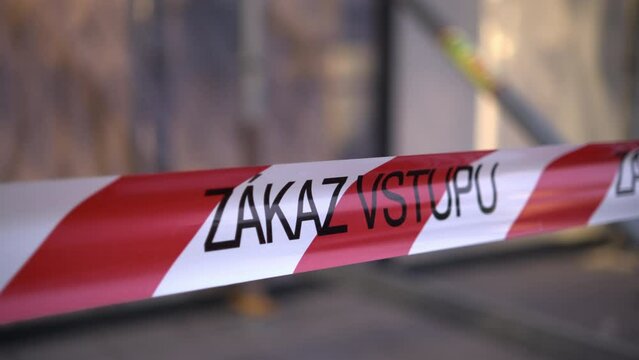 Signal red and white ribbon with Czech inscription Zakaz vstupu forbids entrance to place in city. Warning sign on blurred background closeup