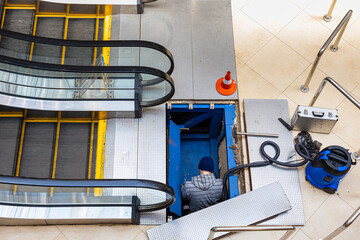   worker repairing escalator mechanism