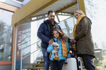 Ukrainian refugee family with luggage at railway station together, Ukrainian war concept.