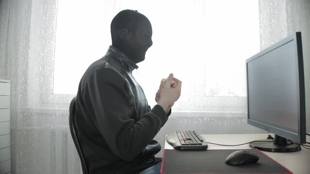 Cyber hacker in a black stocking on his head rubs his hands and looks at the camera. Website hacking concept, cyber attack