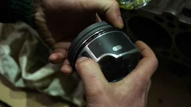 assembling a car engine installing piston rings on a piston