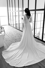 Gorgeous bride in a white wedding dress with a long train. Black and white photo