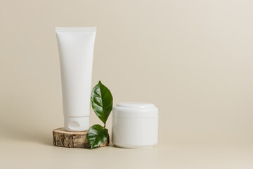 Obraz na płótnie Canvas Mockup unbranded tube face cream on wooden stand with cream bottle and green leaf, organic cosmetic, pastel background, copy space