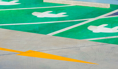 Traffic yellow arrow sign with electric plug sign on green and white concrete floor to show the...