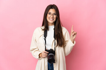 Young photographer Brazilian girl isolated on pink background showing and lifting a finger in sign of the best