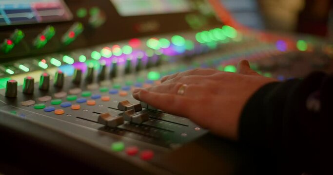 Sound Engineer Hand Controlling Audio on Mixer Console at Live Music Concert. Sound technician professional Works on Mixing Board in Studio or at Night Party. 4K close up handheld shot