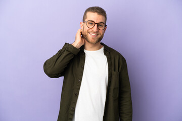 Young handsome caucasian man isolated on purple background laughing