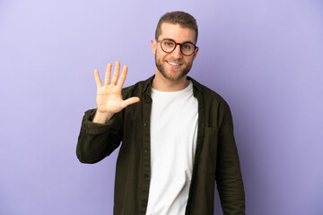 Young handsome caucasian man isolated on purple background counting five with fingers