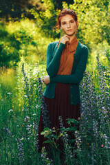 portrait of a beautiful girl with brown hair among the flowers in the field. summer holiday with flowers. countryside