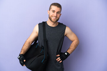 Young sport man with sport bag isolated on white background posing with arms at hip and smiling