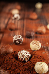 Chocolate pralines, selective focus of chocolate pralines on wooden background with cocoa powder. chocolate concept idea background photo.