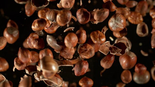 Super Slow Motion Shot of Flying Hazelnuts and Nut Shells Towards Camera on Black at 1000fps.