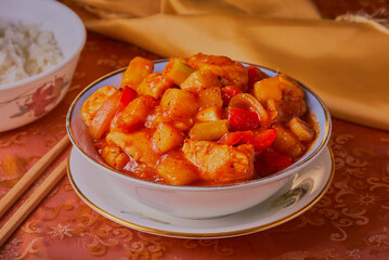Sweet and sour chicken with chopsticks and a bowl of rice.