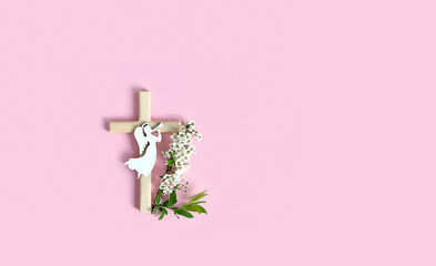 wooden christianity cross, angel and flowers on pink background. symbol of Easter holiday. spring...