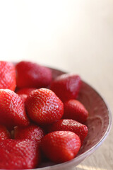 Pink bowl full of fresh strawberries on wooden table. Selective focus.