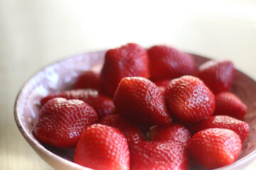 Pink bowl full of fresh strawberries on wooden table. Selective focus.