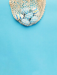 easter colorful painted eggs in the cotton string bag on blue background. banner