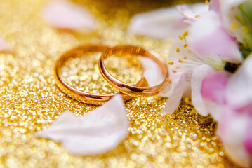 Gold wedding rings and Apple blossoms on a Golden background
