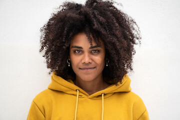 Portrait of beautiful girl with afro hairstyle looking at the camera, posing on the white wall. Natural beauty.