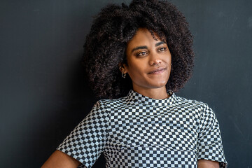 Portrait of young beautiful girl with afro hairstyle and natural makeup posing on the black studio background, looking away. Fashion photo.