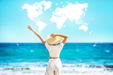 Conceptual photo of a women wearing straw hat, enjoying sunny time at the beach. Back view. World map shaped clouds in the blue sky. Travel. Tourism.