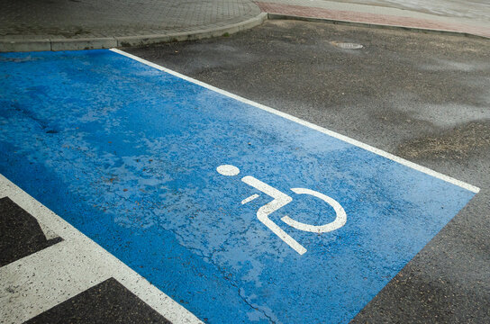 International handicapped symbol painted in bright blue on a shopping center parking space.