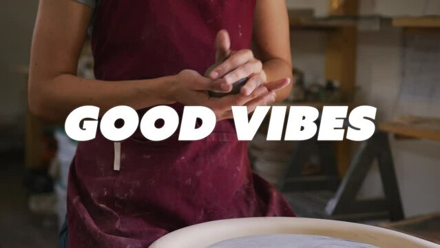 Animation of good vibes text over hands of biracial woman forming pottery