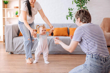 a little girl takes her first steps with the help of her parents. lesbians. The concept of a happy family.