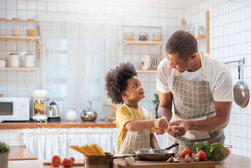 Happy Black African American Father and little son cooking together in kitchen. Brazilian Single...
