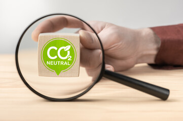 CO2 Neutral sign through magnifying glass on table. CO2 Neutral Written On Wooden Blocks. Reduce...