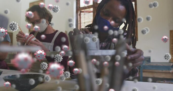 Animation of virus cells over diverse workers with face masks painting pottery