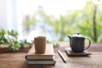 Wooden tea cup and vintage black tea pot on wooden table